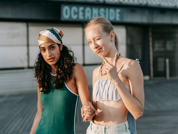Two young women hand in hand on a boardwalk.